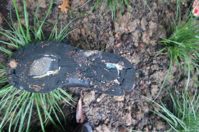 Schuhsohle auf dem Boden liegend, verdeckt Gras und Erde.